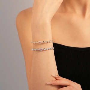 Close-up of gold and silver bracelets featuring pink oval zircon stones and micro-pave diamonds