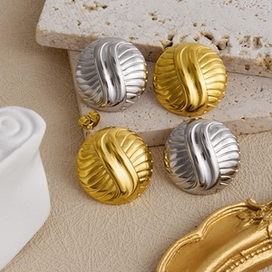Detail view of round gold and silver stud earrings with spiral texture on stone