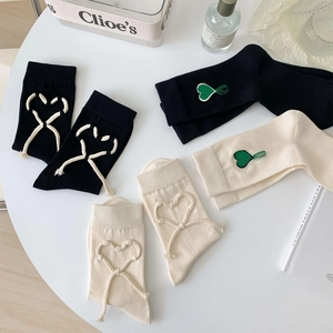 Dettaglio di calzini in cotone con nodo a cuore fatto a mano e ricamo a cuore verde