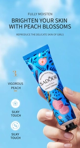 Detailopname van SADOER Perzik handcrème tube met floraal ontwerp en blauwe verpakking
