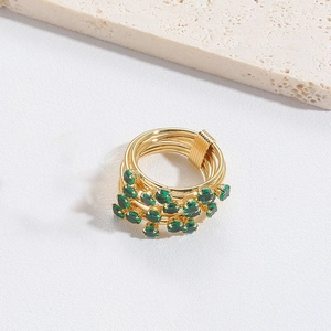 Detail view of gold multi-layer wrap ring featuring clustered green round gemstones
