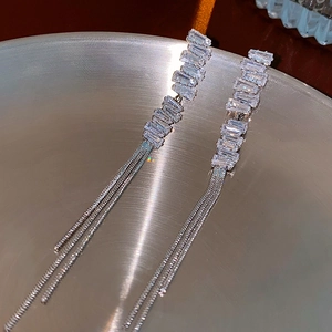 Detailed macro view of cascading tassel earrings with sparkling baguette zircons and silver chains