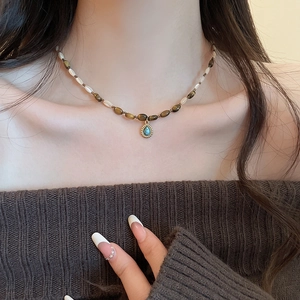 Detailed view of beaded necklace featuring faux tiger eye stone and turquoise drop pendant