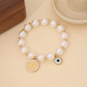 Detail of beaded evil eye bracelet with gold coin charm on a white ceramic plate