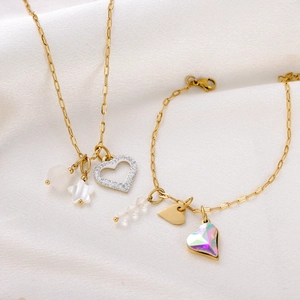 Detail of gold necklace and bracelet set with shell star and crystal heart charms