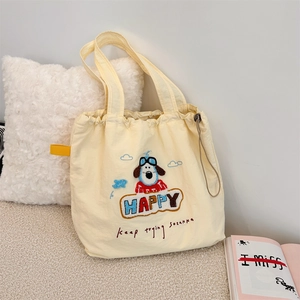 Close-up of cute dog embroidery and Happy lettering on cream canvas shoulder bag