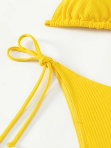 Macro detail of bright yellow ribbed knit bikini with adjustable side tie knot