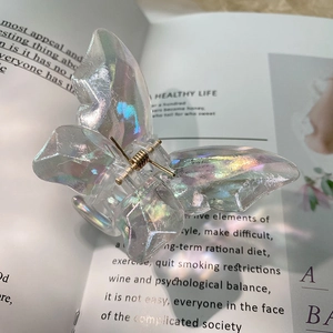 Iridescent butterfly hair claw clip with resin finish and golden spring on a magazine