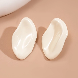 Macro view of cream irregular geometric resin stud earrings on a minimalist background