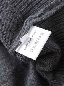 Macro shot of a knitwear care label showing 100% polyester material and washing icons