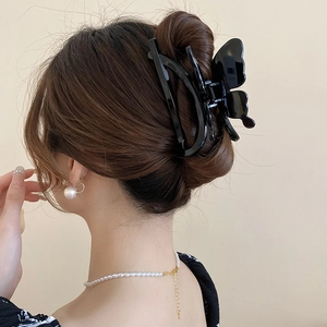 Elegant black acrylic butterfly hair claw clip for women in a stylish updo hairstyle