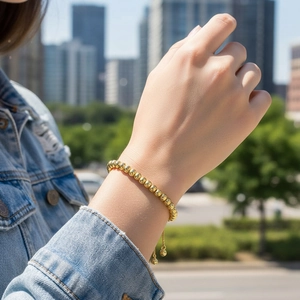 Outdoor shot of a 18K gold-plated beaded bracelet with adjustable drawstring on a model
