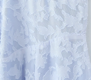 Macro view of light blue lace fabric with white floral relief patterns for women's dress