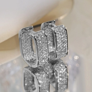 Macro shot of silver rectangular hoop earrings with glitter texture and mirror reflection