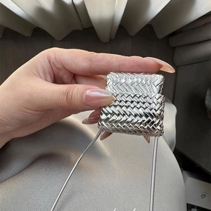 Gros plan d'un pendentif mini sac tressé argenté avec une chaîne en métal brillant