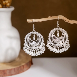 Macro shot of vintage silver-tone peacock bell tassel earrings with hollow leaf design