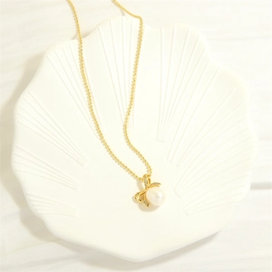 Detail of freshwater pearl pendant with gold bow and diamonds on a ceramic tray