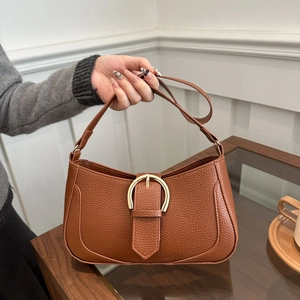 Brown litchi texture leather underarm bag with gold D-buckle shown in a hand-held view