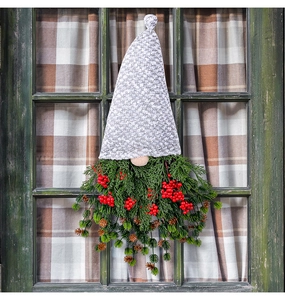 Detail of Christmas gnome wreath with white lace hat and red berries on a green wooden window