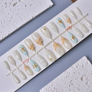 Ocean-themed press-on nails with pearls, 3D starfish and shell textures on blue base