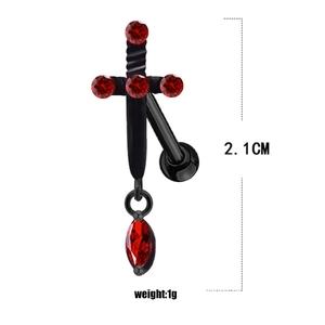 Macro detail of Gothic cross body piercing with red crystal inlay on black metal base