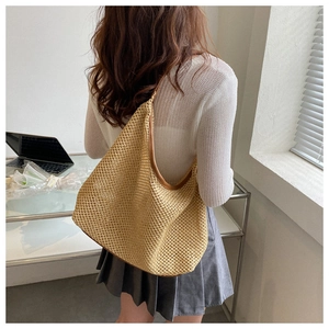 Detailed view of beige woven shoulder bag styled with white top and pleated skirt
