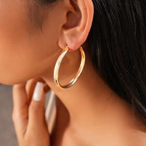 Close-up of model wearing polished gold geometric hoop earring with high-shine finish