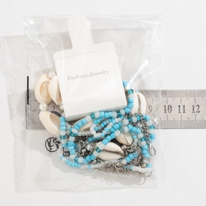 Detail of beaded shell necklace with ruler showing dimensions on white background