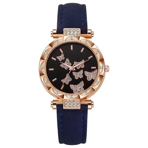 Dettaglio orologio oro rosa con quadrante a farfalla e cinturino in pelle blu