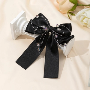 Elegant black satin bow hair clip with translucent beads on a white pillar stand