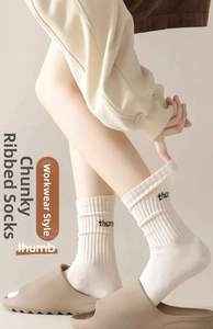 Détail de chaussettes plissées blanc crème avec broderie thumb et texture côtelée