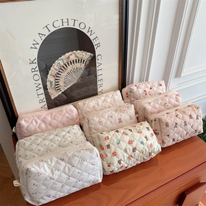 Quilted fabric cosmetic bags with floral, cherry, and bear patterns on a wooden surface