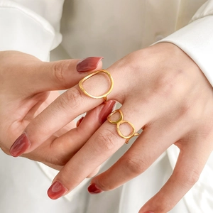 Detailed view of polished gold geometric hollow rings worn in a stylish layered look
