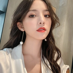 Close-up of elegant long pearl tassel earrings on model with golden metal accents