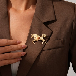 Close-up of vintage gold horse brooch with brown gemstone on a brown suit lapel
