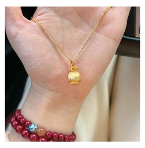 Detailaufnahme einer mattgoldenen Glücksbeutel-Halskette mit Zirkon-Akzenten