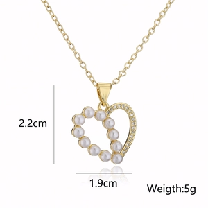 Macro detail of gold-plated heart pendant with pearls and crystals, size 2.2x1.9cm