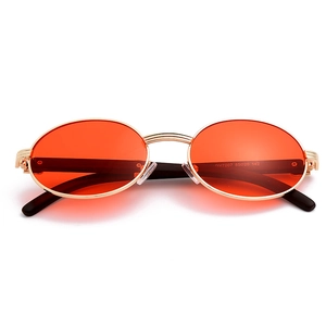 Detalle de gafas de sol ovaladas retro con lentes naranjas y montura metálica dorada