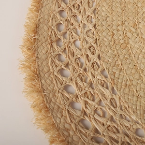 Macro detail of natural raffia weave patterns and fringe edge on a sun hat