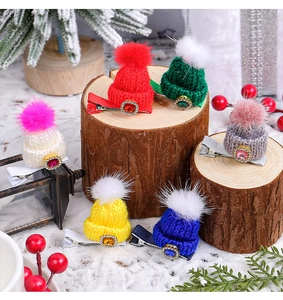 Close-up of colorful knitted Christmas hat hair clips with pompons on snow background