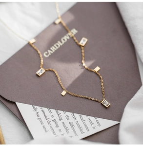 Macro shot of gold tassel necklace featuring square crystal pendants on a fine chain