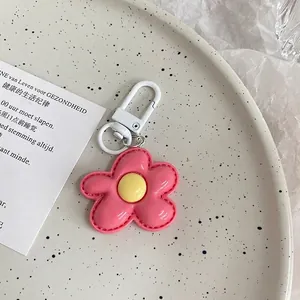 Close-up of pink flower keychain with yellow center and white carabiner hook on tray
