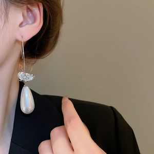 Détail de boucles d'oreilles fleur argentée avec longues perles blanches en gouttes