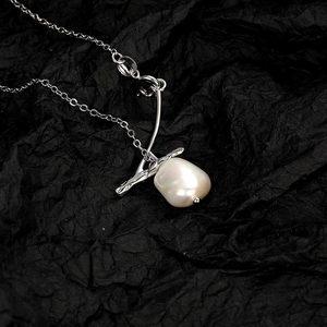 Baroque freshwater pearl necklace with silver branch pendant on black textured background