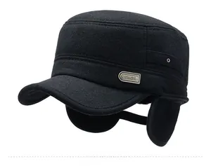 Detail of winter flat cap with ear flaps and metallic emblem on black wool fabric