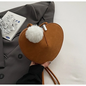 Makro-Detail der herzförmigen Wildledertasche in Karamell mit weißem Plüsch-Anhänger