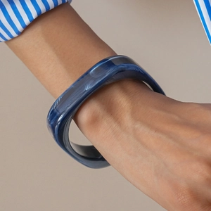 Close-up of a blue marble texture resin square bangle worn on a model's wrist