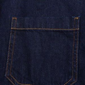 Détail de la poche arrière en jean bleu foncé avec surpiqûres orange et texture sergé