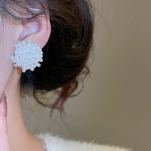 Boucles d'oreilles élégantes en perles en forme de fleur portées par un mannequin