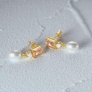 Detailed macro view of S925 silver pearl earring with orange zircon on stone background
